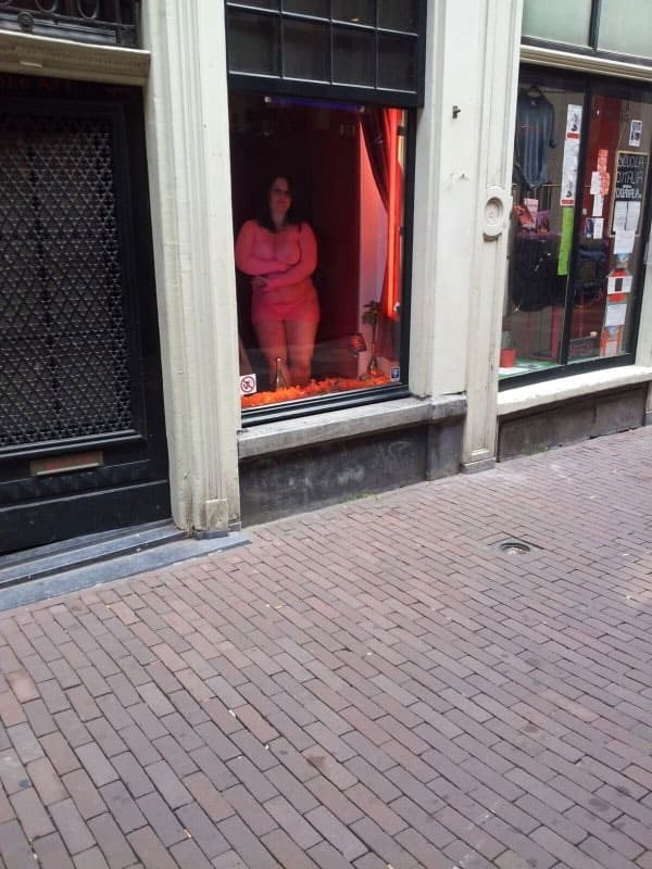 Проститутка в витрине борделя заманивает клиентов с улицы 1 из 12 фото