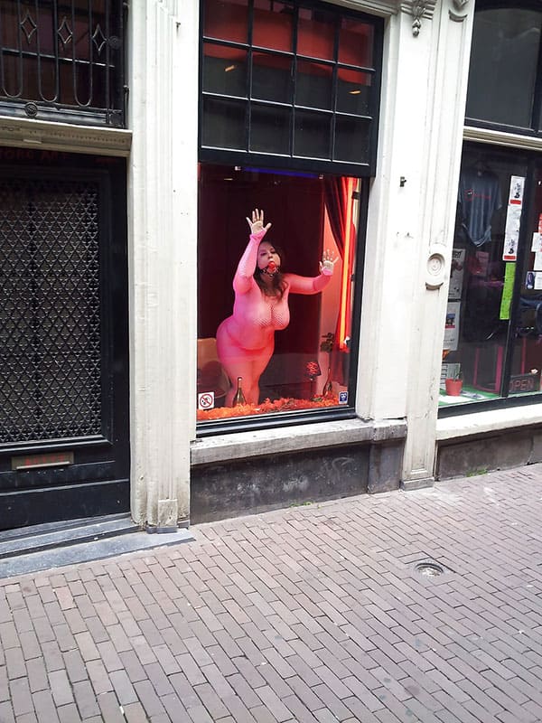 Проститутка в витрине борделя заманивает клиентов с улицы 12 из 12 фото