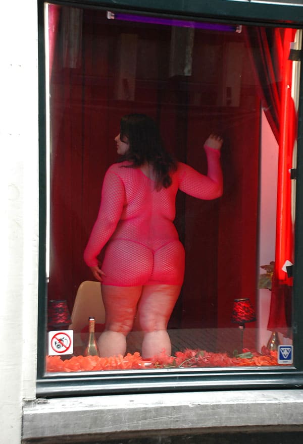 Проститутка в витрине борделя заманивает клиентов с улицы 7 из 12 фото
