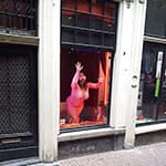 Проститутка в витрине борделя заманивает клиентов с улицы